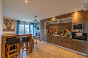 a kitchen with wooden cabinets and a bar with chairs at Au bord de la Loire - Île de Nantes in Nantes
