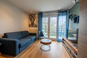 a living room with a blue couch and a tv at Au bord de la Loire - Île de Nantes in Nantes
