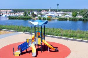 a playground with a slide in front of a river at Apolonia Apartamenty III - SPA in Dziwnów