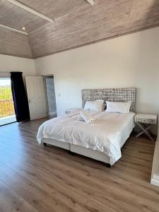 Un dormitorio con una cama grande y suelo de madera. en 120 on Lyme, en St Francis Bay