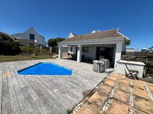 a patio with a blue pool in front of a house at 120 on Lyme in St Francis Bay
