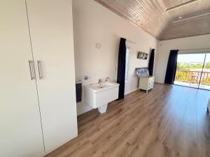 a bathroom with a white sink and a wooden floor at 120 on Lyme in St Francis Bay +18 photos