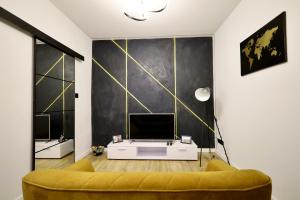 a living room with a yellow couch and a television at Apartament Wroclawska SELF CHECK-IN 24H in Bytom
