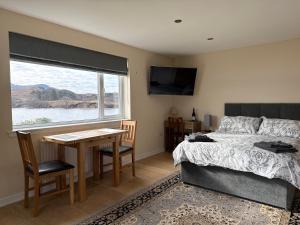 a bedroom with a bed and a table and a window at Loch Morar Private Suite in Mallaig
