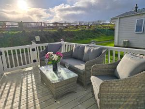 a deck with couches and a table with flowers on it at Cornwall Caravan Retreat 3 Crantock in Crantock