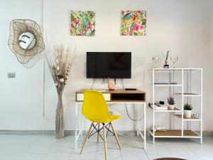 a living room with a desk and a yellow chair at PLAYMAR Maspalomas Bungalow 124 Bali Style with terrace in Maspalomas