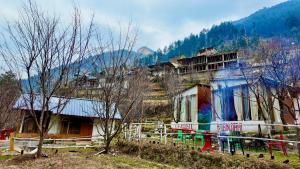 Acoustic heaven Cottage jibhi في Jibhi: مجموعة منازل على تلة مع سياج