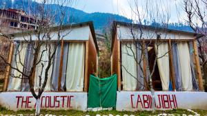 Acoustic heaven Cottage jibhi في Jibhi: منزل صغير مع باب أخضر وأشجار