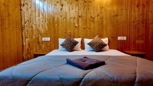 Acoustic heaven Cottage jibhi في Jibhi: غرفة نوم بسرير كبير وبجدران خشبية