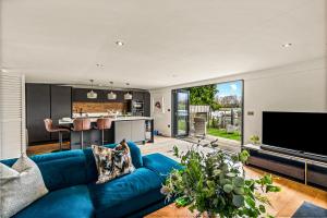 a living room with a blue couch and a kitchen at River cabin & Mills Cottage in Henley on Thames