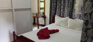 a bedroom with a white bed with red sheets and pillows at Sigiri Inn in Kibissa