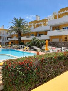 a swimming pool with a palm tree and a building at Royal Cabanas Golf by Amandio Batista in Cabanas de Tavira
