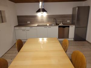 a kitchen with a wooden table with chairs and a refrigerator at Monteurwohnung Landshut in Vilsheim +4 photos