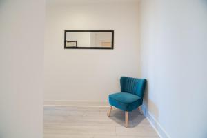 a blue chair in a white room with a mirror at Argyle Place in Glasgow