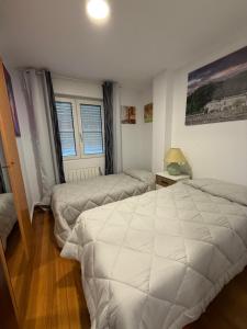 a bedroom with a white bed and a table and window at Apartamento AJO 2 habitaciones piscina y tenis in Ajo +23 photos