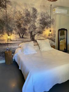 a bedroom with a white bed with a painting on the wall at Le Domaine Saint Jean in Saint-Saturnin-les-Apt