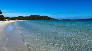 a beach with blue water and mountains in the background at Villa Porra 100m2, pleine nature, piscine, vue mer in Porto-Vecchio +1 photo