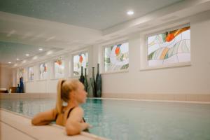 a woman sitting in a swimming pool at Arthotel Gratschwirt in Dobbiaco