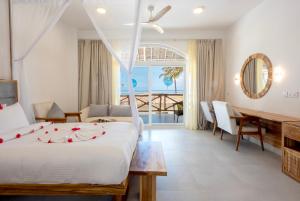 a bedroom with a bed and a table and a view of the ocean at Royal Mandarin Hotel & Resort Zanzibar in Pwani Mchangani