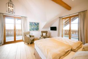 una camera da letto con un letto, una sedia e finestre di Forthuber Landhaus - Self Check-in möglich a Feldkirchen bei Mattighofen