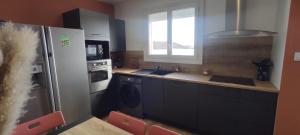 a kitchen with a refrigerator and a sink at L'Escapade Morinière Sam Suffy in La Séguinière