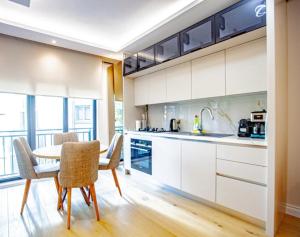 Una cocina con gabinetes blancos y una mesa y sillas. en Mayer Skycon Residence in Beşiktaş 2, en Estambul