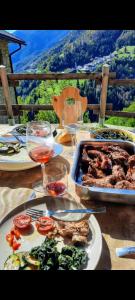 una tavola con piatti di cibo e bicchieri di vino di Chalet-Tabià al Sol montagna Dolomiti Pecol a San Tomaso