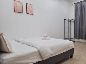 a teddy bear sitting on a bed in a bedroom at Westay Guest House in Melaka