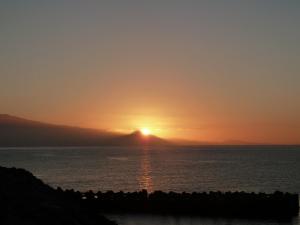 a sunset over the ocean with a mountain in the background at Große Dachwohnung mit Blick auf das Meer in Valle Gran Rey