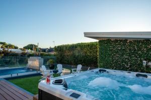 雪莉海滩Luxury Beach House - Heated Private Pool & Heated Spa - Fire Pitt - Walk to Beach & Golf的游泳池旁甲板上的热水浴池