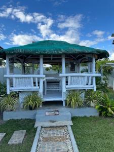 a gazebo with two white benches and a green roof at Covenant Farmhouse in Evangelista