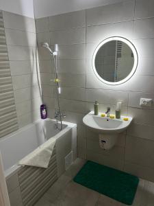 un bagno con un lavandino, una vasca e uno specchio di Uno Retreat Residence a Braşov