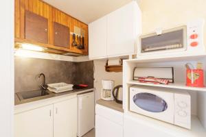a kitchen with white cabinets and a microwave at Le Nid de Gourette - Au Pied des Pistes in Eaux-Bonnes
