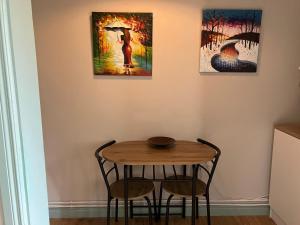 a table with two chairs and two paintings on the wall at Iniscealtra Mini Bedsit Studio in Mountshannon