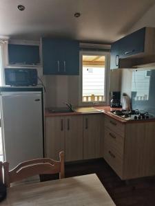 a kitchen with blue cabinets and a white refrigerator at Gaby mobil Home in Port-la-Nouvelle +1 photo
