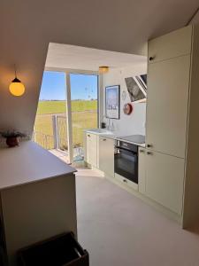 Una cocina con gabinetes blancos y una ventana grande. en Large holiday apartment, en Ebeltoft