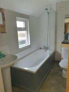 a bathroom with a tub and a sink and a toilet at Beautiful House in Stoke in Audley