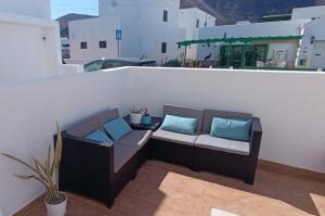 a brown couch with blue pillows on a balcony at Home2Book Cozy Dúplex & Spacious Terrace in Órzola in Orzola