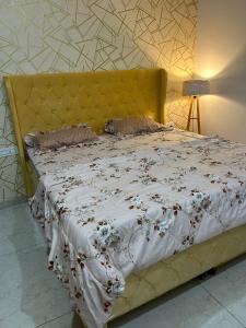 a bedroom with a bed with a yellow headboard at Aerogreen Homestays in Zirakpur