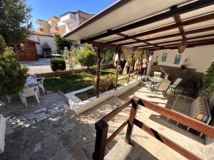 a patio with a wooden pergola and chairs and tables at Къща с четири спални двор с барбекю in Néa Péramos