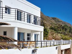 a white house with a hill in the background at Coral Vistas Self Catering Apartments in Gordonʼs Bay