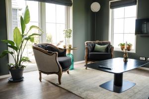 a living room with two chairs and a coffee table at De Os aan de Dijk 2 in Grafhorst