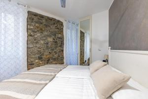 łóżko w pokoju z kamienną ścianą w obiekcie La Corte - Seta apartment Bellagio w mieście Bellagio