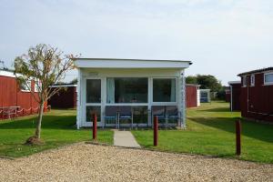 a tiny house in a yard with a porch at Sea Lavender Holiday Chalet, close to sandy beach in Heacham