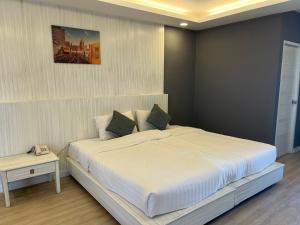 a bedroom with a large white bed and a phone at Curve Boutique Hotel in Pattaya Central +9 photos