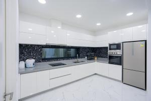 a white kitchen with white cabinets and appliances at My Havana, pool villa in Ban Nong Pru