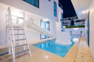 a house with a slide and a swimming pool at My Havana, pool villa in Ban Nong Pru