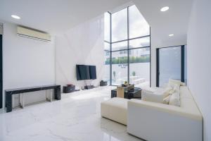a white living room with a white couch and a tv at My Havana, pool villa in Ban Nong Pru