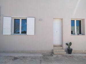 a white house with two windows and a potted plant at Milleventi in Marsala