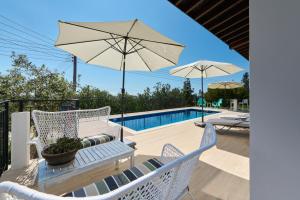 a patio with chairs and an umbrella and a pool at Villa Nomi in Peyia